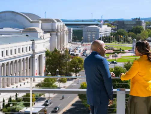 Two people looking out on Union Station with cars below 